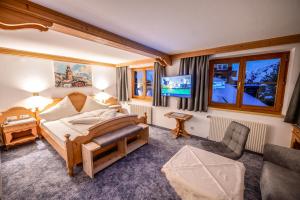 a bedroom with a bed and a chair and a tv at Pension Berger in Oberlech