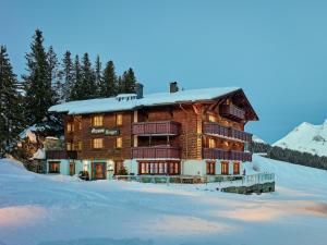 a large log building with snow on the ground at Pension Berger in Oberlech