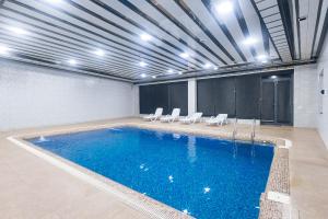 ein großes Schwimmbecken mit Liegestühlen in einem Gebäude in der Unterkunft Fergana hotel in Fargʻona