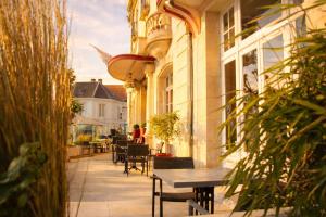 a patio with a table and chairs and a building at LOGIS Hotel Majestic Chatelaillon Plage - La Rochelle in Châtelaillon-Plage
