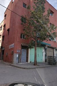 a red building with a tree in front of it at Dar Noor El Chams in Salé