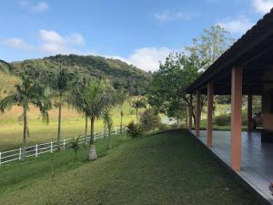 a house with a lawn with palm trees and a fence at Miracatu! Refúgio e Paz nas Montanhas in Miracatu