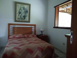 a bedroom with a bed and a picture on the wall at Miracatu! Refúgio e Paz nas Montanhas in Miracatu