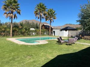 a backyard with a swimming pool and two chairs and palm trees at Elqui LU ASPAR in Vicuña