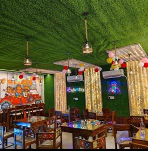 a restaurant with tables and chairs and a green ceiling at MMB Hotel in Bikaner
