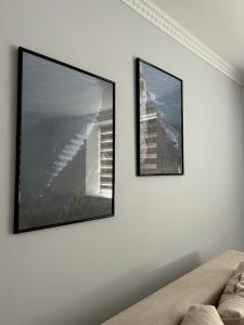two framed pictures on a white wall with a couch at Woodside House in Solotvyno