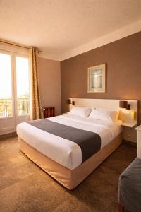 a large bed in a room with a large window at LOGIS Hotel Majestic Chatelaillon Plage - La Rochelle in Châtelaillon-Plage