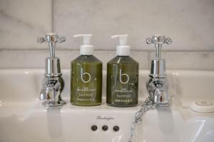 two bottles of soap and two faucets on a sink at Virginia Cottage in York +43 photos