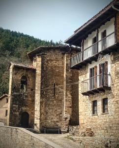 a stone building with a balcony on the side of it at Albergue Armaia Artepea in Urzainqui