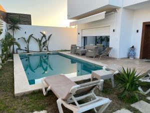 a swimming pool with two lounge chairs and a house at Dar Selima Hammamet in Hammamet
