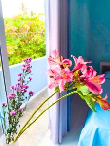 a vase filled with pink flowers next to a window at The Shore Residence in Hikkaduwa