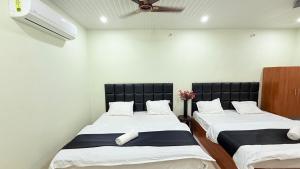 two twin beds in a room with a ceiling fan at Hotel Blessing Inn & Restaurant in Prayagraj