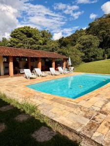 a swimming pool with chairs and a house at Sítio Toca da Pedra in Pedra Bela