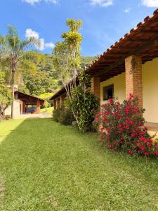 a house with red flowers in the yard at Sítio Toca da Pedra in Pedra Bela