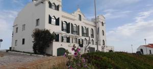 a large white building with purple flowers in front of it at Casa das Marés 3 in Baleal