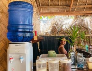 Eine Frau sitzt an einem Tisch, auf dem ein großer blauer Topf steht. in der Unterkunft Camp Laya Daracoton Island in El Nido