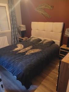 a bedroom with a large bed with a large headboard at Maison cosy in Biganos
