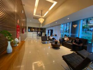 a lobby with people sitting on couches in a building at Excelente Flat Duplex com vaga de garagem no Fusion Hotel in Brasília +12 photos