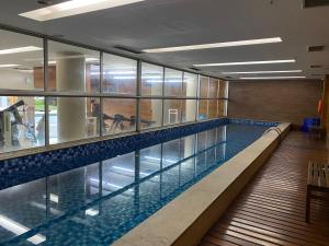 a swimming pool in a building with a large window at Excelente Flat Duplex com vaga de garagem no Fusion Hotel in Brasília