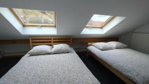 two beds in a room with two windows at Duplex avec vue au centre de Bussang in Bussang