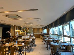 a dining room with tables and chairs and windows at Excelente Flat Duplex com vaga de garagem no Fusion Hotel in Brasília
