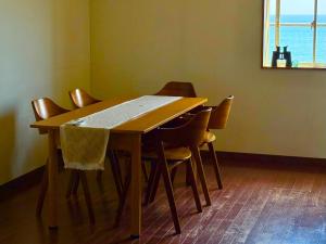 a wooden table with chairs in a room with a window at Pavilion Beachfront in Shishikui