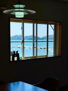 two cats sitting in a window looking out at the ocean at Pavilion Beachfront in Shishikui