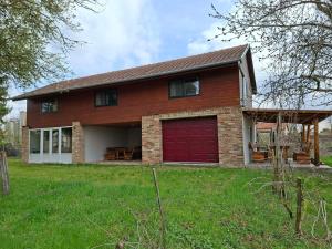 a house with a red garage door and a yard at Mara Ház in Lengyel