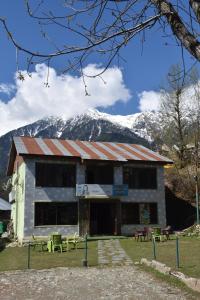 a building with a snow covered mountain in the background at Dreamland Cottage in Pahalgām