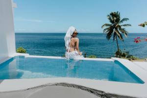 a woman in a white dress standing next to a swimming pool at Bintana Sa Paraiso in Mambajao