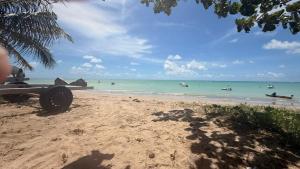 a beach with boats in the water and a palm tree at Flats Privativos MaragoJulios in Maragogi