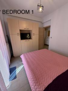 a bedroom with a pink bed and a television at Castle view 2 in Kavála