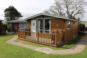a large wooden cabin with a large deck at Chalet 24 in Seaton
