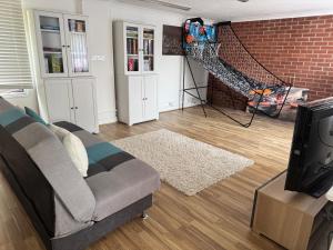 a living room with a couch and a tv at The pool house in Bedford