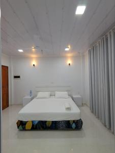 a white bedroom with a bed in a room at Rihiveli Palace in Maamigili