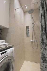 a shower with a washing machine in a bathroom at Stylish studio in the centre in Helsinki +17 photos