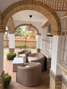 an outdoor patio with wicker furniture and an archway at Hotel Victoria Matalascañas in Matalascañas