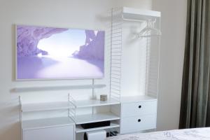 a white dresser with a tv on a wall at Stylish studio in the centre in Helsinki