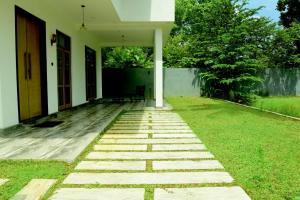 a garden with a stone walkway in front of a house at Abey Villa Madiha Beach Surf Stay in Matara