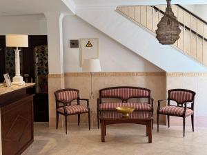 a room with three chairs and a table and stairs at Hotel Victoria Matalascañas in Matalascañas +21 photos