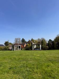 a field of grass with a house in the background at The pool house in Bedford
