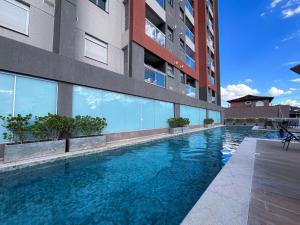 a swimming pool in front of a building at Ribeirão Premium Apogeo in Ribeirão Preto
