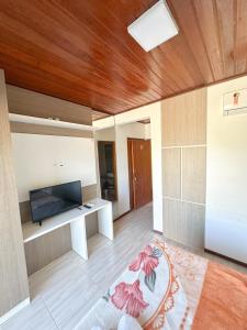 a living room with a flat screen tv on a wooden ceiling at Hotel 5km da Guarda do Embaú in Palhoça