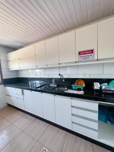a kitchen with white cabinets and a black counter top at Hotel 5km da Guarda do Embaú in Palhoça