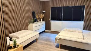 a bedroom with two beds and a dresser and a window at Kastanjegaarden in Ansager