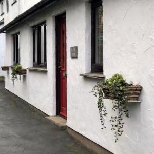 a white building with a red door and windows at Last Yan - Stylish Ambleside Stay in Ambleside