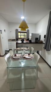 a glass table with white chairs in a kitchen at Bangalô com Quarto, Sala, Varanda in Maceió