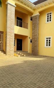 a large yellow house with two pillars at Bold 3 Bedroom Apartments in Abuja