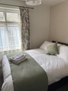a white bed with a green pillow and a window at Hideway Dartmouth in Dartmouth