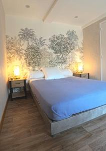 a bedroom with a large bed with blue sheets and trees on the wall at Le casse noisettes in Gourin
